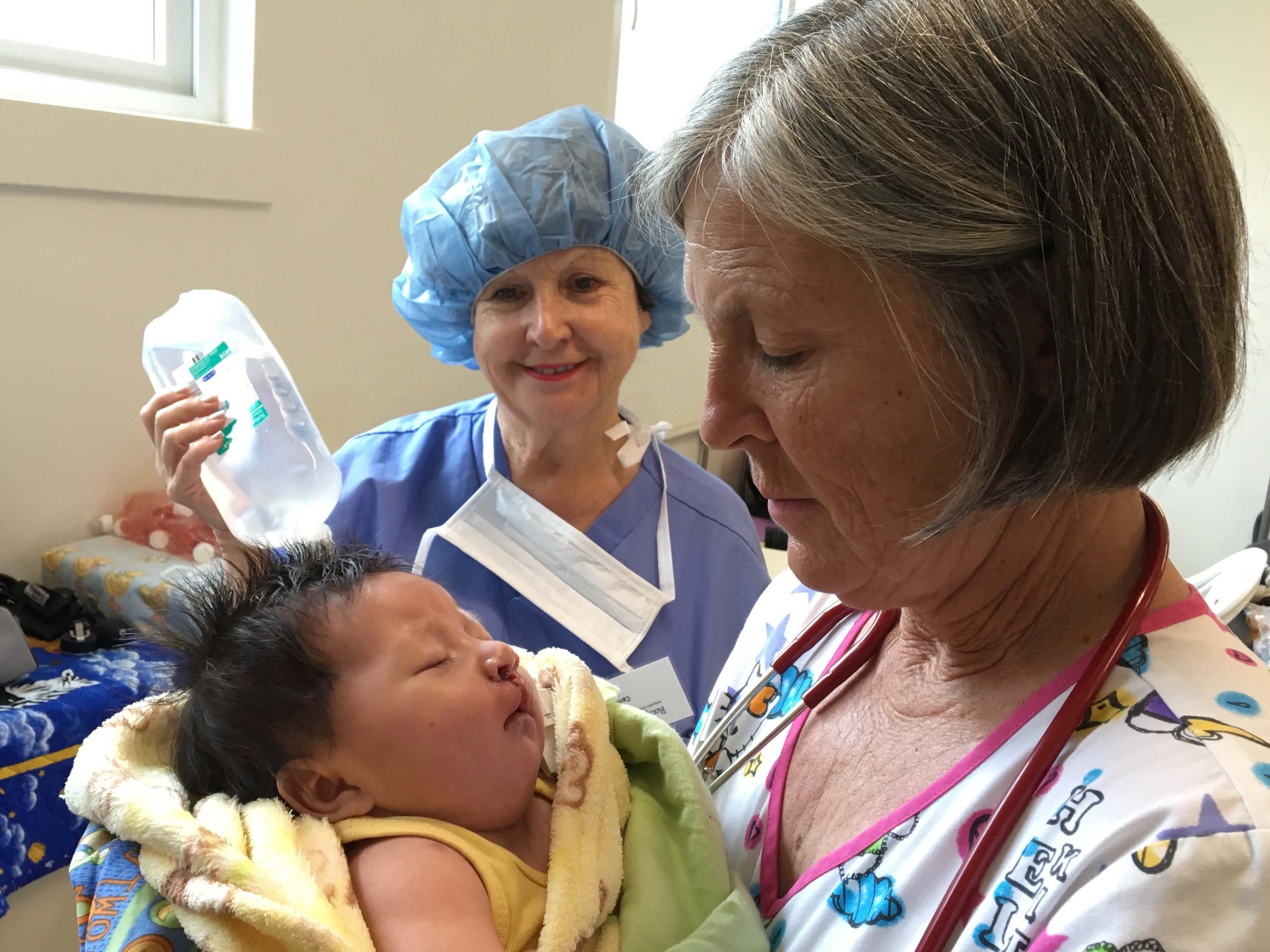 Translator Carmen Sigler and Lead Pediatrician Paula Rand treat a child in the recovery room (PACU).